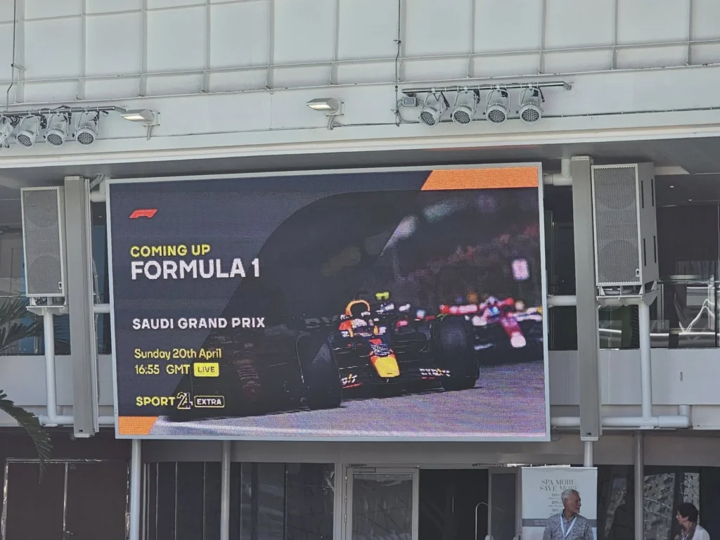 Rotterdam Cruise Port: Our Complete Guide + Insider Tips 2026 (Visited 5 Times Since 2022 by Danny and Peter) 18 Cruising with Danny and Peter, Holland America Line, Nieuw Statendam, Rotterdam, The Netherlands, Voyage Rotterdam Nieuw Statendam Embarkation | A vibrant collage capturing embarkation day on Holland America’s Nieuw Statendam docked at Rotterdam’s Cruise Terminal, with the Erasmus Bridge and Zalmhaventoren in the background under a golden afternoon sky. The ship’s elegant atrium sparkles with a chandelier, while a cozy Oceanview Family Cabin showcases bunk beds and large windows framing the Nieuwe Maas. A family tours the Lido Market, where tables overflow with herb-crusted lamb, chocolate eggs, and colorful desserts for Easter lunch. On deck, two teenagers snap selfies against Rotterdam’s twinkling skyline during sail away, the ship gliding past the illuminated Swan Bridge. In the Ocean Bar, friends toast with cocktails, and the Crow’s Nest lounge offers panoramic views of the river. The scene closes with a cozy cabin moment, a TV glowing with Formula 1 action, hot chocolate mugs on a table, and the gentle sway of the ship at dusk.