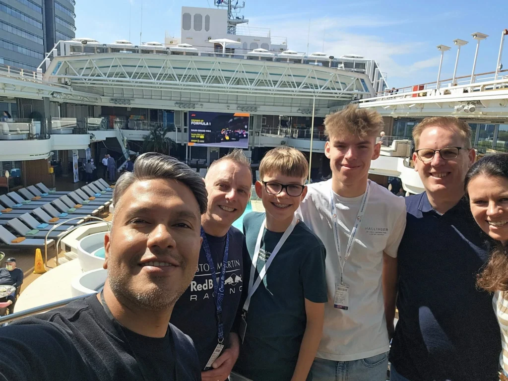 Rotterdam Cruise Port: Our Complete Guide + Insider Tips 2026 (Visited 5 Times Since 2022 by Danny and Peter) 3 Cruising with Danny and Peter, Holland America Line, Nieuw Statendam, Rotterdam, The Netherlands, Voyage Rotterdam Nieuw Statendam Embarkation | A vibrant collage capturing embarkation day on Holland America’s Nieuw Statendam docked at Rotterdam’s Cruise Terminal, with the Erasmus Bridge and Zalmhaventoren in the background under a golden afternoon sky. The ship’s elegant atrium sparkles with a chandelier, while a cozy Oceanview Family Cabin showcases bunk beds and large windows framing the Nieuwe Maas. A family tours the Lido Market, where tables overflow with herb-crusted lamb, chocolate eggs, and colorful desserts for Easter lunch. On deck, two teenagers snap selfies against Rotterdam’s twinkling skyline during sail away, the ship gliding past the illuminated Swan Bridge. In the Ocean Bar, friends toast with cocktails, and the Crow’s Nest lounge offers panoramic views of the river. The scene closes with a cozy cabin moment, a TV glowing with Formula 1 action, hot chocolate mugs on a table, and the gentle sway of the ship at dusk.