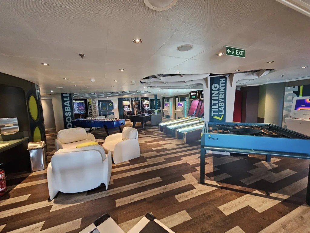 Rotterdam Cruise Port: Our Complete Guide + Insider Tips 2026 (Visited 5 Times Since 2022 by Danny and Peter) 19 Cruising with Danny and Peter, Holland America Line, Nieuw Statendam, Rotterdam, The Netherlands, Voyage Rotterdam Nieuw Statendam Embarkation | A vibrant collage capturing embarkation day on Holland America’s Nieuw Statendam docked at Rotterdam’s Cruise Terminal, with the Erasmus Bridge and Zalmhaventoren in the background under a golden afternoon sky. The ship’s elegant atrium sparkles with a chandelier, while a cozy Oceanview Family Cabin showcases bunk beds and large windows framing the Nieuwe Maas. A family tours the Lido Market, where tables overflow with herb-crusted lamb, chocolate eggs, and colorful desserts for Easter lunch. On deck, two teenagers snap selfies against Rotterdam’s twinkling skyline during sail away, the ship gliding past the illuminated Swan Bridge. In the Ocean Bar, friends toast with cocktails, and the Crow’s Nest lounge offers panoramic views of the river. The scene closes with a cozy cabin moment, a TV glowing with Formula 1 action, hot chocolate mugs on a table, and the gentle sway of the ship at dusk.