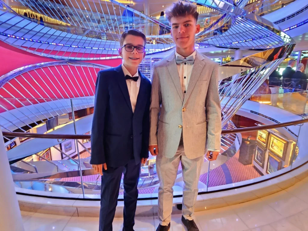 A Voyage Through Time and Tide: Exploring the English Channel Aboard Holland America Line’s Nieuw Statendam 10 Cruising with Danny and Peter, Holland America Line, Nieuw Statendam, English Channel, Sea Day, English Channel Nieuw Statendam Sea Day Experience | A luxurious scene aboard Holland America Line’s Nieuw Statendam cruising the English Channel, featuring the Main Dining Room with elegantly set tables, gourmet dishes like eggs Benedict, and large windows revealing gray-green waves; the intimate Pinnacle Grill with plush seating and a plated beef tenderloin with lobster dumplings; the World Stage theater’s circular stage and vibrant 270-degree LED screen displaying Casablanca’s Hassan II Mosque; and the ship’s sleek white hull sailing smoothly under an overcast sky, embodying modern cruising elegance.