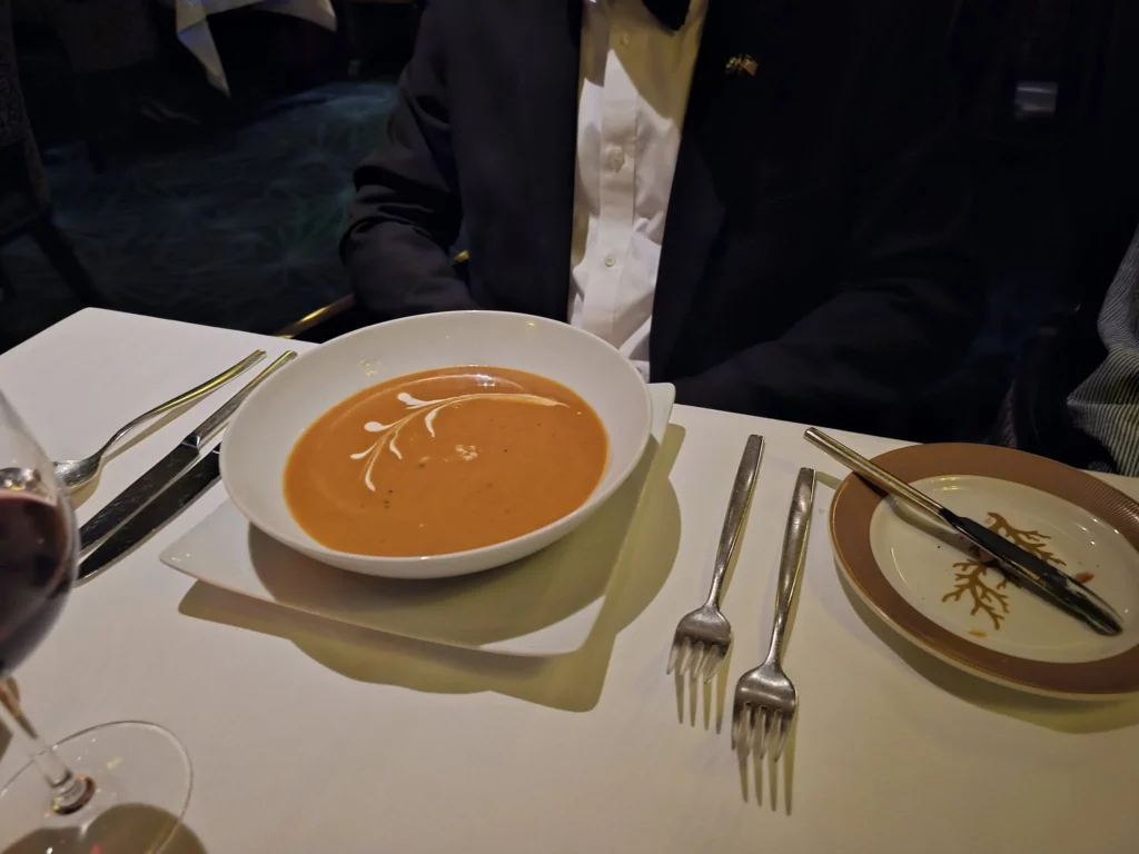 A Voyage Through Time and Tide: Exploring the English Channel Aboard Holland America Line’s Nieuw Statendam 26 Cruising with Danny and Peter, Holland America Line, Nieuw Statendam, English Channel, Sea Day, English Channel Nieuw Statendam Sea Day Experience | A luxurious scene aboard Holland America Line’s Nieuw Statendam cruising the English Channel, featuring the Main Dining Room with elegantly set tables, gourmet dishes like eggs Benedict, and large windows revealing gray-green waves; the intimate Pinnacle Grill with plush seating and a plated beef tenderloin with lobster dumplings; the World Stage theater’s circular stage and vibrant 270-degree LED screen displaying Casablanca’s Hassan II Mosque; and the ship’s sleek white hull sailing smoothly under an overcast sky, embodying modern cruising elegance.