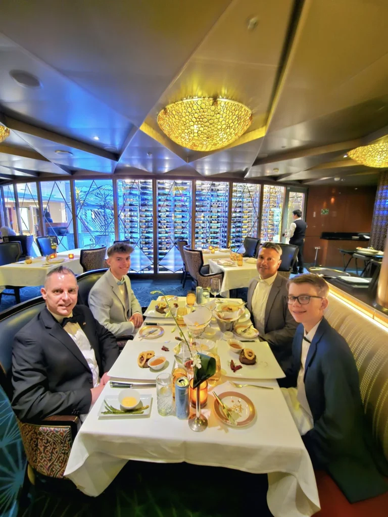 A Voyage Through Time and Tide: Exploring the English Channel Aboard Holland America Line’s Nieuw Statendam 31 Cruising with Danny and Peter, Holland America Line, Nieuw Statendam, English Channel, Sea Day, English Channel Nieuw Statendam Sea Day Experience | A luxurious scene aboard Holland America Line’s Nieuw Statendam cruising the English Channel, featuring the Main Dining Room with elegantly set tables, gourmet dishes like eggs Benedict, and large windows revealing gray-green waves; the intimate Pinnacle Grill with plush seating and a plated beef tenderloin with lobster dumplings; the World Stage theater’s circular stage and vibrant 270-degree LED screen displaying Casablanca’s Hassan II Mosque; and the ship’s sleek white hull sailing smoothly under an overcast sky, embodying modern cruising elegance.