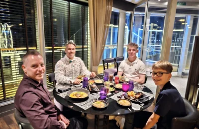 Cruising with Danny and Peter, Holland America Line, Nieuw Statendam, Bay Of Biscay History Sea Day | A scenic view of the Bay of Biscay’s deep blue waters under a partly cloudy sky, with gentle waves reflecting sunlight, alongside the elegant Dining Room of Holland America’s Nieuw Statendam, featuring white tablecloths, polished silverware, and a plate of lobster Benedict with hollandaise sauce. The World Stage theater showcases a vibrant LED screen displaying Agadir’s bustling souk with colorful spices and crafts, while the Lido Pool area glows at night with twinkling lights, where guests mingle with champagne during the Mariners Reception. The intimate Tamarind restaurant, with warm wood decor, presents a beautifully plated Penang red curry with duck, paired with a sake flight.