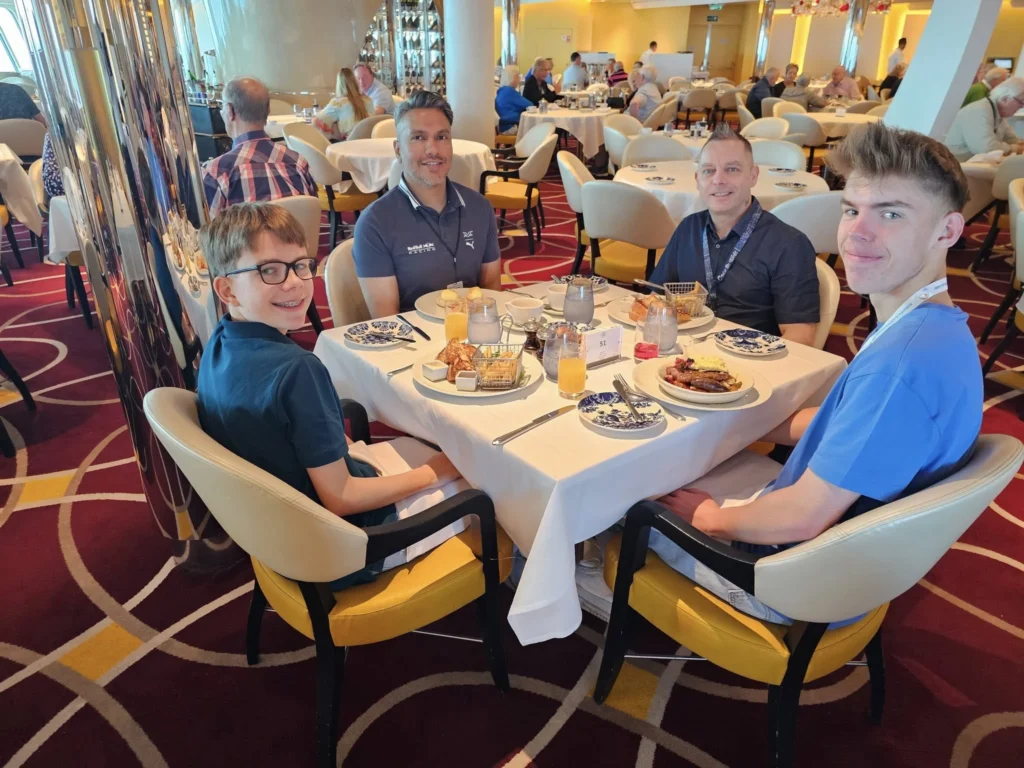 Cruising with Danny and Peter, Holland America Line, Nieuw Statendam, Bay Of Biscay History Sea Day | A scenic view of the Bay of Biscay’s deep blue waters under a partly cloudy sky, with gentle waves reflecting sunlight, alongside the elegant Dining Room of Holland America’s Nieuw Statendam, featuring white tablecloths, polished silverware, and a plate of lobster Benedict with hollandaise sauce. The World Stage theater showcases a vibrant LED screen displaying Agadir’s bustling souk with colorful spices and crafts, while the Lido Pool area glows at night with twinkling lights, where guests mingle with champagne during the Mariners Reception. The intimate Tamarind restaurant, with warm wood decor, presents a beautifully plated Penang red curry with duck, paired with a sake flight.