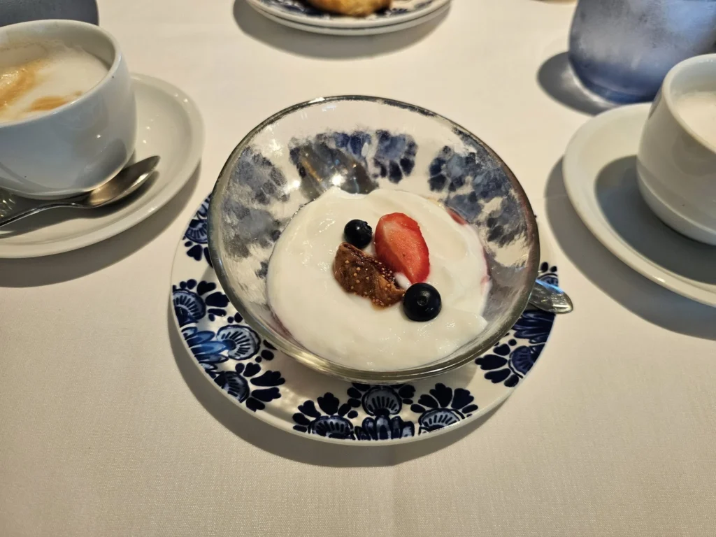 Cruising with Danny and Peter, Holland America Line, Nieuw Statendam, Bay Of Biscay History Sea Day | A scenic view of the Bay of Biscay’s deep blue waters under a partly cloudy sky, with gentle waves reflecting sunlight, alongside the elegant Dining Room of Holland America’s Nieuw Statendam, featuring white tablecloths, polished silverware, and a plate of lobster Benedict with hollandaise sauce. The World Stage theater showcases a vibrant LED screen displaying Agadir’s bustling souk with colorful spices and crafts, while the Lido Pool area glows at night with twinkling lights, where guests mingle with champagne during the Mariners Reception. The intimate Tamarind restaurant, with warm wood decor, presents a beautifully plated Penang red curry with duck, paired with a sake flight.