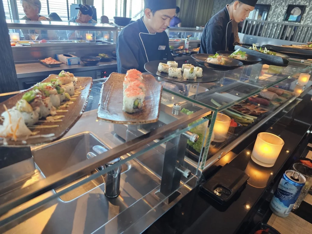 Cruising with Danny and Peter, Holland America Line, Nieuw Statendam, Atlantic Ocean Sea Day Experience | A vibrant collage capturing a sea day on Holland America’s Nieuw Statendam: a panoramic view of the Atlantic Ocean’s deep blue waves under golden sunlight from the ship’s deck; an elegant breakfast of eggs Benedict and coffee in the Main Dining Room with ocean-view windows; a digital iris collage with colorful, galaxy-like patterns created in the Explorations Central lounge; and a lively Cassidy Robertson & Company performance on the World Stage, featuring dancers in vibrant costumes against a futuristic LED backdrop.