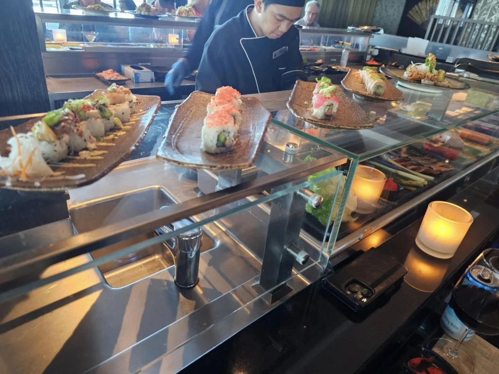 Cruising with Danny and Peter, Holland America Line, Nieuw Statendam, Atlantic Ocean Sea Day Experience | A vibrant collage capturing a sea day on Holland America’s Nieuw Statendam: a panoramic view of the Atlantic Ocean’s deep blue waves under golden sunlight from the ship’s deck; an elegant breakfast of eggs Benedict and coffee in the Main Dining Room with ocean-view windows; a digital iris collage with colorful, galaxy-like patterns created in the Explorations Central lounge; and a lively Cassidy Robertson & Company performance on the World Stage, featuring dancers in vibrant costumes against a futuristic LED backdrop.