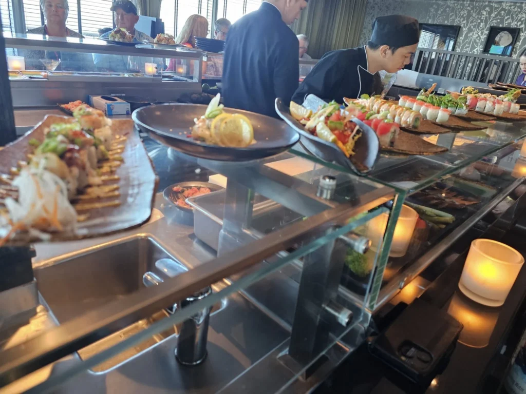 Cruising with Danny and Peter, Holland America Line, Nieuw Statendam, Atlantic Ocean Sea Day Experience | A vibrant collage capturing a sea day on Holland America’s Nieuw Statendam: a panoramic view of the Atlantic Ocean’s deep blue waves under golden sunlight from the ship’s deck; an elegant breakfast of eggs Benedict and coffee in the Main Dining Room with ocean-view windows; a digital iris collage with colorful, galaxy-like patterns created in the Explorations Central lounge; and a lively Cassidy Robertson & Company performance on the World Stage, featuring dancers in vibrant costumes against a futuristic LED backdrop.