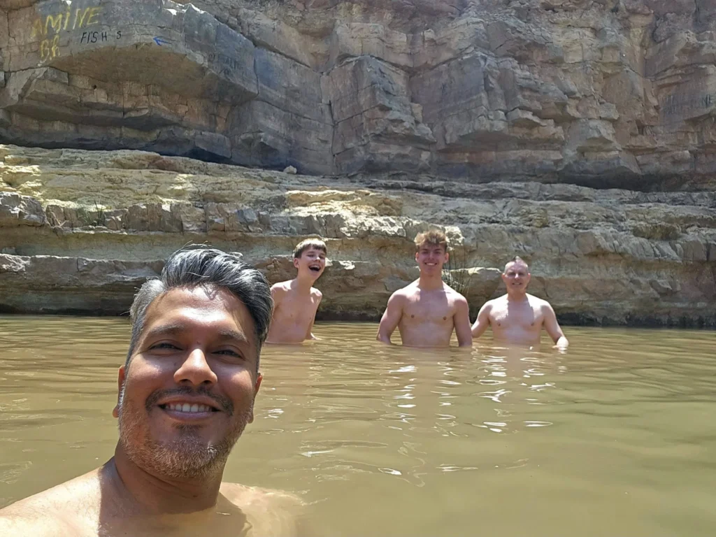 Cruising with Danny and Peter, Holland America Line, Nieuw Statendam, Agadir Morocco Adventure | A vibrant collage capturing a day in Agadir, Morocco, during a Holland America Nieuw Statendam cruise: the white façade and green-tiled minaret of Mosque Mohammed V gleaming under the sun; the bustling Agadir Marina with yachts bobbing in the harbor and golden beach sands stretching toward the Anti-Atlas Mountains; the historic Agadir Oufella kasbah ruins on a hill overlooking the sparkling Atlantic; Sven riding a camel along a scenic path with a Berber handler; the colorful chaos of Souk El Had market with stalls of spices, rugs, and jewelry; the lush Paradise Valley oasis with palm trees, clear pools, and tiny fish nibbling at feet; and an aromatic garden with Moroccan bread, argan oil, and mint tea under a shaded canopy.