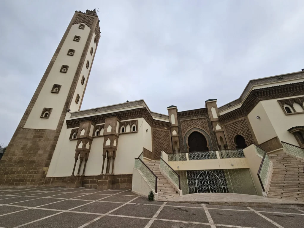 Cruising with Danny and Peter, Holland America Line, Nieuw Statendam, Agadir Morocco Adventure | A vibrant collage capturing a day in Agadir, Morocco, during a Holland America Nieuw Statendam cruise: the white façade and green-tiled minaret of Mosque Mohammed V gleaming under the sun; the bustling Agadir Marina with yachts bobbing in the harbor and golden beach sands stretching toward the Anti-Atlas Mountains; the historic Agadir Oufella kasbah ruins on a hill overlooking the sparkling Atlantic; Sven riding a camel along a scenic path with a Berber handler; the colorful chaos of Souk El Had market with stalls of spices, rugs, and jewelry; the lush Paradise Valley oasis with palm trees, clear pools, and tiny fish nibbling at feet; and an aromatic garden with Moroccan bread, argan oil, and mint tea under a shaded canopy.