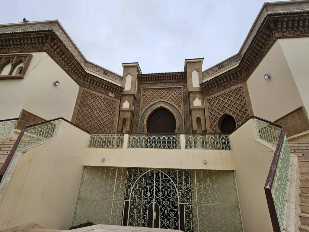 Cruising with Danny and Peter, Holland America Line, Nieuw Statendam, Agadir Morocco Adventure | A vibrant collage capturing a day in Agadir, Morocco, during a Holland America Nieuw Statendam cruise: the white façade and green-tiled minaret of Mosque Mohammed V gleaming under the sun; the bustling Agadir Marina with yachts bobbing in the harbor and golden beach sands stretching toward the Anti-Atlas Mountains; the historic Agadir Oufella kasbah ruins on a hill overlooking the sparkling Atlantic; Sven riding a camel along a scenic path with a Berber handler; the colorful chaos of Souk El Had market with stalls of spices, rugs, and jewelry; the lush Paradise Valley oasis with palm trees, clear pools, and tiny fish nibbling at feet; and an aromatic garden with Moroccan bread, argan oil, and mint tea under a shaded canopy.