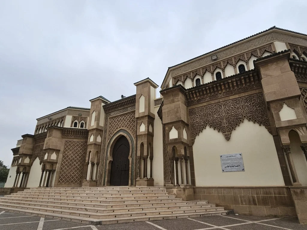 Cruising with Danny and Peter, Holland America Line, Nieuw Statendam, Agadir Morocco Adventure | A vibrant collage capturing a day in Agadir, Morocco, during a Holland America Nieuw Statendam cruise: the white façade and green-tiled minaret of Mosque Mohammed V gleaming under the sun; the bustling Agadir Marina with yachts bobbing in the harbor and golden beach sands stretching toward the Anti-Atlas Mountains; the historic Agadir Oufella kasbah ruins on a hill overlooking the sparkling Atlantic; Sven riding a camel along a scenic path with a Berber handler; the colorful chaos of Souk El Had market with stalls of spices, rugs, and jewelry; the lush Paradise Valley oasis with palm trees, clear pools, and tiny fish nibbling at feet; and an aromatic garden with Moroccan bread, argan oil, and mint tea under a shaded canopy.