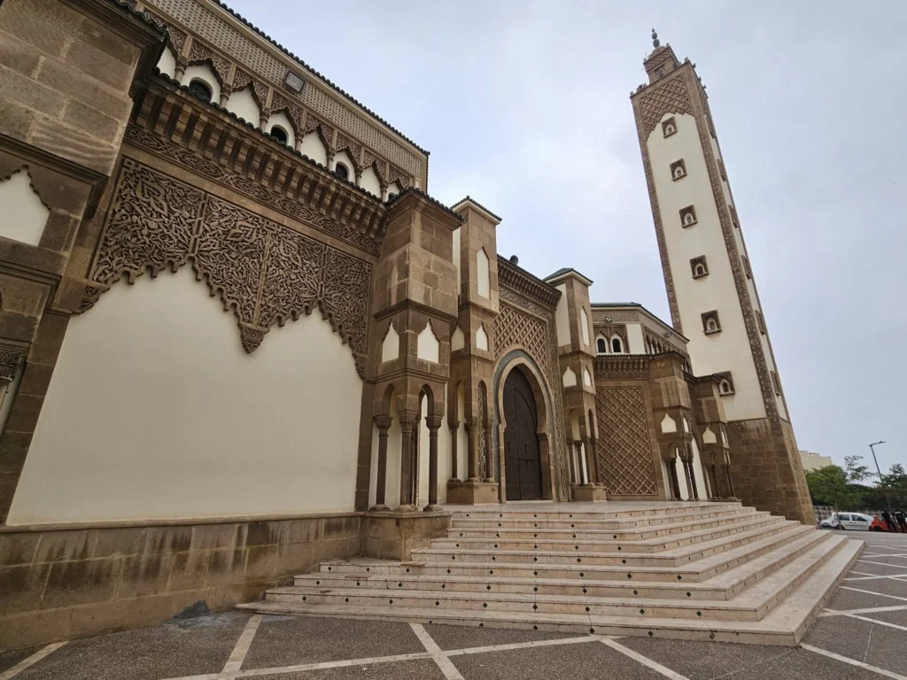 Cruising with Danny and Peter, Holland America Line, Nieuw Statendam, Agadir Morocco Adventure | A vibrant collage capturing a day in Agadir, Morocco, during a Holland America Nieuw Statendam cruise: the white façade and green-tiled minaret of Mosque Mohammed V gleaming under the sun; the bustling Agadir Marina with yachts bobbing in the harbor and golden beach sands stretching toward the Anti-Atlas Mountains; the historic Agadir Oufella kasbah ruins on a hill overlooking the sparkling Atlantic; Sven riding a camel along a scenic path with a Berber handler; the colorful chaos of Souk El Had market with stalls of spices, rugs, and jewelry; the lush Paradise Valley oasis with palm trees, clear pools, and tiny fish nibbling at feet; and an aromatic garden with Moroccan bread, argan oil, and mint tea under a shaded canopy.
