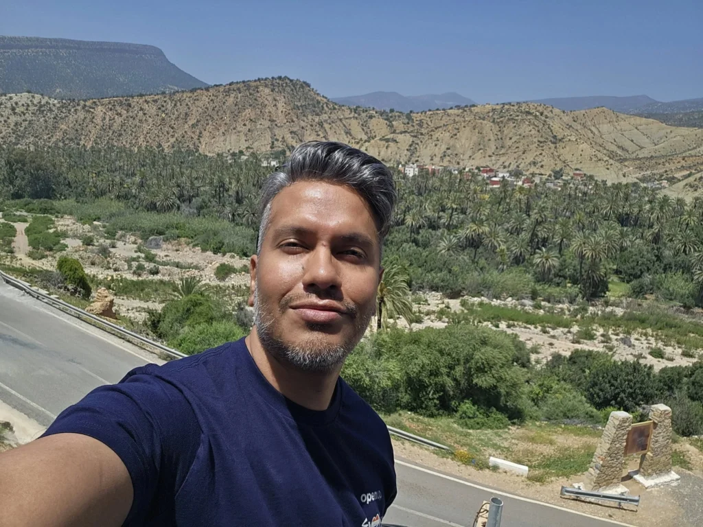 Cruising with Danny and Peter, Holland America Line, Nieuw Statendam, Agadir Morocco Adventure | A vibrant collage capturing a day in Agadir, Morocco, during a Holland America Nieuw Statendam cruise: the white façade and green-tiled minaret of Mosque Mohammed V gleaming under the sun; the bustling Agadir Marina with yachts bobbing in the harbor and golden beach sands stretching toward the Anti-Atlas Mountains; the historic Agadir Oufella kasbah ruins on a hill overlooking the sparkling Atlantic; Sven riding a camel along a scenic path with a Berber handler; the colorful chaos of Souk El Had market with stalls of spices, rugs, and jewelry; the lush Paradise Valley oasis with palm trees, clear pools, and tiny fish nibbling at feet; and an aromatic garden with Moroccan bread, argan oil, and mint tea under a shaded canopy.