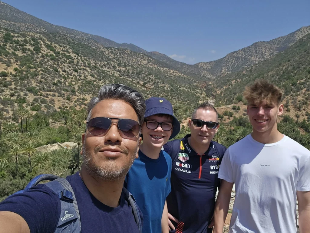 Cruising with Danny and Peter, Holland America Line, Nieuw Statendam, Agadir Morocco Adventure | A vibrant collage capturing a day in Agadir, Morocco, during a Holland America Nieuw Statendam cruise: the white façade and green-tiled minaret of Mosque Mohammed V gleaming under the sun; the bustling Agadir Marina with yachts bobbing in the harbor and golden beach sands stretching toward the Anti-Atlas Mountains; the historic Agadir Oufella kasbah ruins on a hill overlooking the sparkling Atlantic; Sven riding a camel along a scenic path with a Berber handler; the colorful chaos of Souk El Had market with stalls of spices, rugs, and jewelry; the lush Paradise Valley oasis with palm trees, clear pools, and tiny fish nibbling at feet; and an aromatic garden with Moroccan bread, argan oil, and mint tea under a shaded canopy.