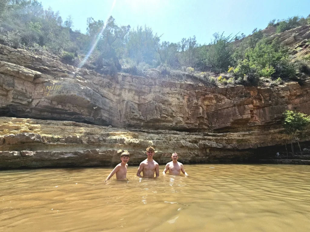 Cruising with Danny and Peter, Holland America Line, Nieuw Statendam, Agadir Morocco Adventure | A vibrant collage capturing a day in Agadir, Morocco, during a Holland America Nieuw Statendam cruise: the white façade and green-tiled minaret of Mosque Mohammed V gleaming under the sun; the bustling Agadir Marina with yachts bobbing in the harbor and golden beach sands stretching toward the Anti-Atlas Mountains; the historic Agadir Oufella kasbah ruins on a hill overlooking the sparkling Atlantic; Sven riding a camel along a scenic path with a Berber handler; the colorful chaos of Souk El Had market with stalls of spices, rugs, and jewelry; the lush Paradise Valley oasis with palm trees, clear pools, and tiny fish nibbling at feet; and an aromatic garden with Moroccan bread, argan oil, and mint tea under a shaded canopy.