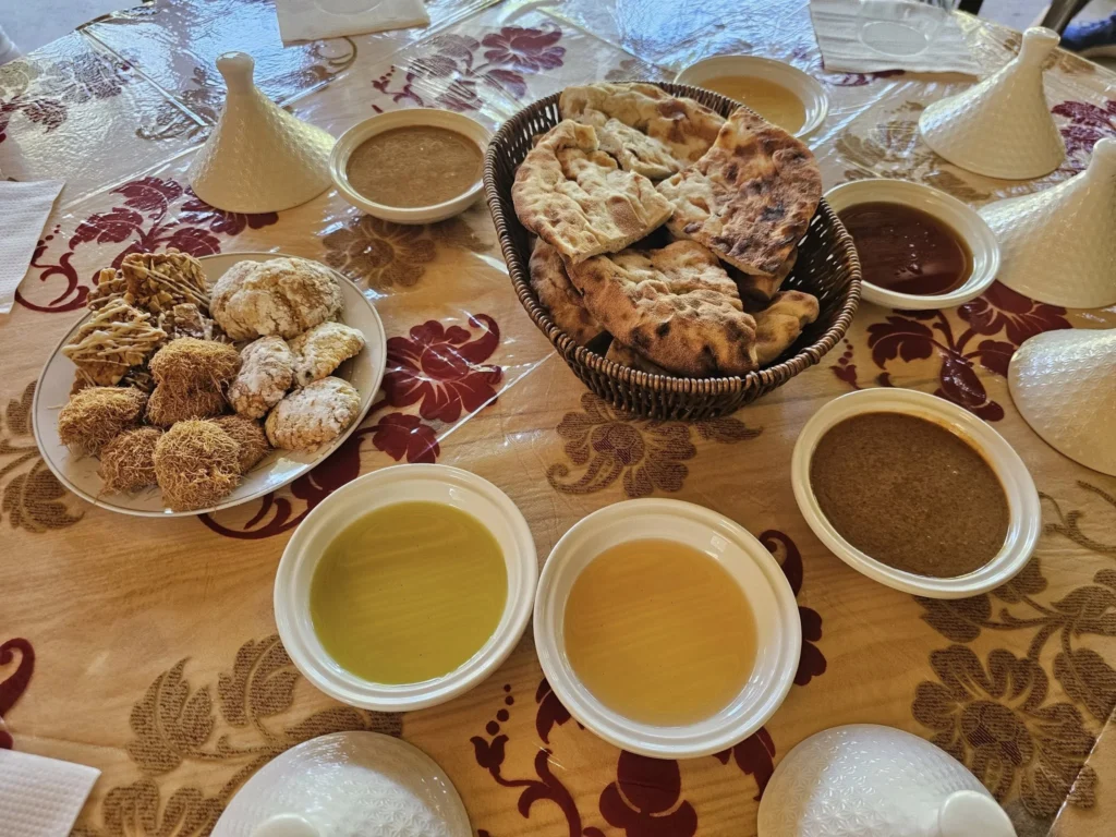 Cruising with Danny and Peter, Holland America Line, Nieuw Statendam, Agadir Morocco Adventure | A vibrant collage capturing a day in Agadir, Morocco, during a Holland America Nieuw Statendam cruise: the white façade and green-tiled minaret of Mosque Mohammed V gleaming under the sun; the bustling Agadir Marina with yachts bobbing in the harbor and golden beach sands stretching toward the Anti-Atlas Mountains; the historic Agadir Oufella kasbah ruins on a hill overlooking the sparkling Atlantic; Sven riding a camel along a scenic path with a Berber handler; the colorful chaos of Souk El Had market with stalls of spices, rugs, and jewelry; the lush Paradise Valley oasis with palm trees, clear pools, and tiny fish nibbling at feet; and an aromatic garden with Moroccan bread, argan oil, and mint tea under a shaded canopy.