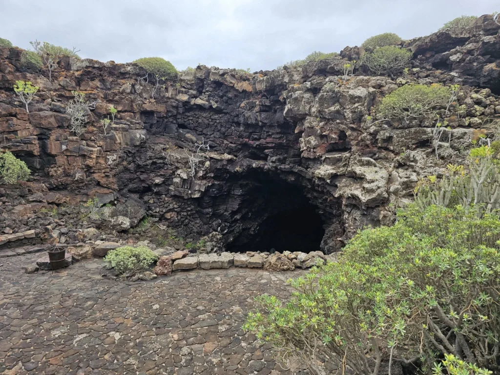 Cruising with Danny and Peter, Holland America Line, Nieuw Statendam, Arrecife, Lanzarote, Canary Islands, Volcanic Adventure | A vibrant collage capturing an adventure in Arrecife, Lanzarote: the dark, winding lava tunnels of Cueva de los Verdes illuminated by soft lights; the serene turquoise pool and lush greenery of Jameos del Agua with its volcanic cave backdrop; the sweeping ocean views from Mirador del Río’s cliffside lookout, framing La Graciosa island; and the surreal, Mars-like red and black lava fields of Timanfaya National Park under a clear sky, showcasing Lanzarote’s volcanic beauty.