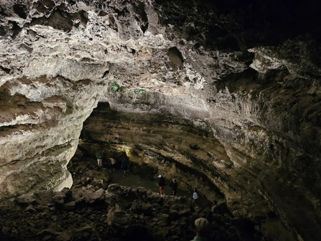 Cruising with Danny and Peter, Holland America Line, Nieuw Statendam, Arrecife, Lanzarote, Canary Islands, Volcanic Adventure | A vibrant collage capturing an adventure in Arrecife, Lanzarote: the dark, winding lava tunnels of Cueva de los Verdes illuminated by soft lights; the serene turquoise pool and lush greenery of Jameos del Agua with its volcanic cave backdrop; the sweeping ocean views from Mirador del Río’s cliffside lookout, framing La Graciosa island; and the surreal, Mars-like red and black lava fields of Timanfaya National Park under a clear sky, showcasing Lanzarote’s volcanic beauty.