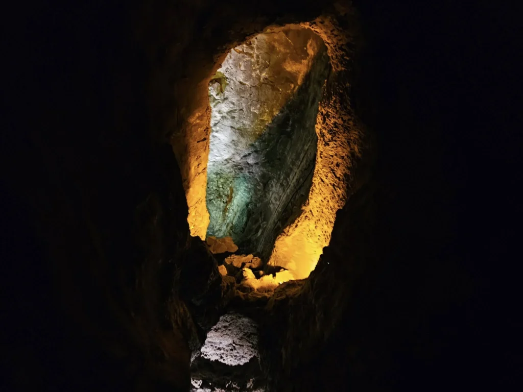 Cruising with Danny and Peter, Holland America Line, Nieuw Statendam, Arrecife, Lanzarote, Canary Islands, Volcanic Adventure | A vibrant collage capturing an adventure in Arrecife, Lanzarote: the dark, winding lava tunnels of Cueva de los Verdes illuminated by soft lights; the serene turquoise pool and lush greenery of Jameos del Agua with its volcanic cave backdrop; the sweeping ocean views from Mirador del Río’s cliffside lookout, framing La Graciosa island; and the surreal, Mars-like red and black lava fields of Timanfaya National Park under a clear sky, showcasing Lanzarote’s volcanic beauty.