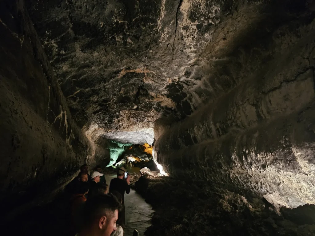 Cruising with Danny and Peter, Holland America Line, Nieuw Statendam, Arrecife, Lanzarote, Canary Islands, Volcanic Adventure | A vibrant collage capturing an adventure in Arrecife, Lanzarote: the dark, winding lava tunnels of Cueva de los Verdes illuminated by soft lights; the serene turquoise pool and lush greenery of Jameos del Agua with its volcanic cave backdrop; the sweeping ocean views from Mirador del Río’s cliffside lookout, framing La Graciosa island; and the surreal, Mars-like red and black lava fields of Timanfaya National Park under a clear sky, showcasing Lanzarote’s volcanic beauty.
