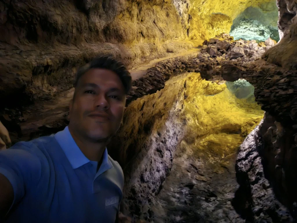 Cruising with Danny and Peter, Holland America Line, Nieuw Statendam, Arrecife, Lanzarote, Canary Islands, Volcanic Adventure | A vibrant collage capturing an adventure in Arrecife, Lanzarote: the dark, winding lava tunnels of Cueva de los Verdes illuminated by soft lights; the serene turquoise pool and lush greenery of Jameos del Agua with its volcanic cave backdrop; the sweeping ocean views from Mirador del Río’s cliffside lookout, framing La Graciosa island; and the surreal, Mars-like red and black lava fields of Timanfaya National Park under a clear sky, showcasing Lanzarote’s volcanic beauty.