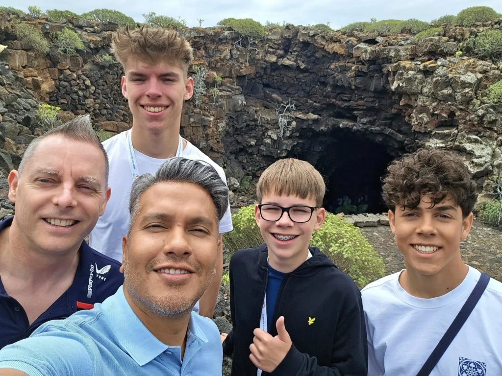 Cruising with Danny and Peter, Holland America Line, Nieuw Statendam, Arrecife, Lanzarote, Canary Islands, Volcanic Adventure | A vibrant collage capturing an adventure in Arrecife, Lanzarote: the dark, winding lava tunnels of Cueva de los Verdes illuminated by soft lights; the serene turquoise pool and lush greenery of Jameos del Agua with its volcanic cave backdrop; the sweeping ocean views from Mirador del Río’s cliffside lookout, framing La Graciosa island; and the surreal, Mars-like red and black lava fields of Timanfaya National Park under a clear sky, showcasing Lanzarote’s volcanic beauty.