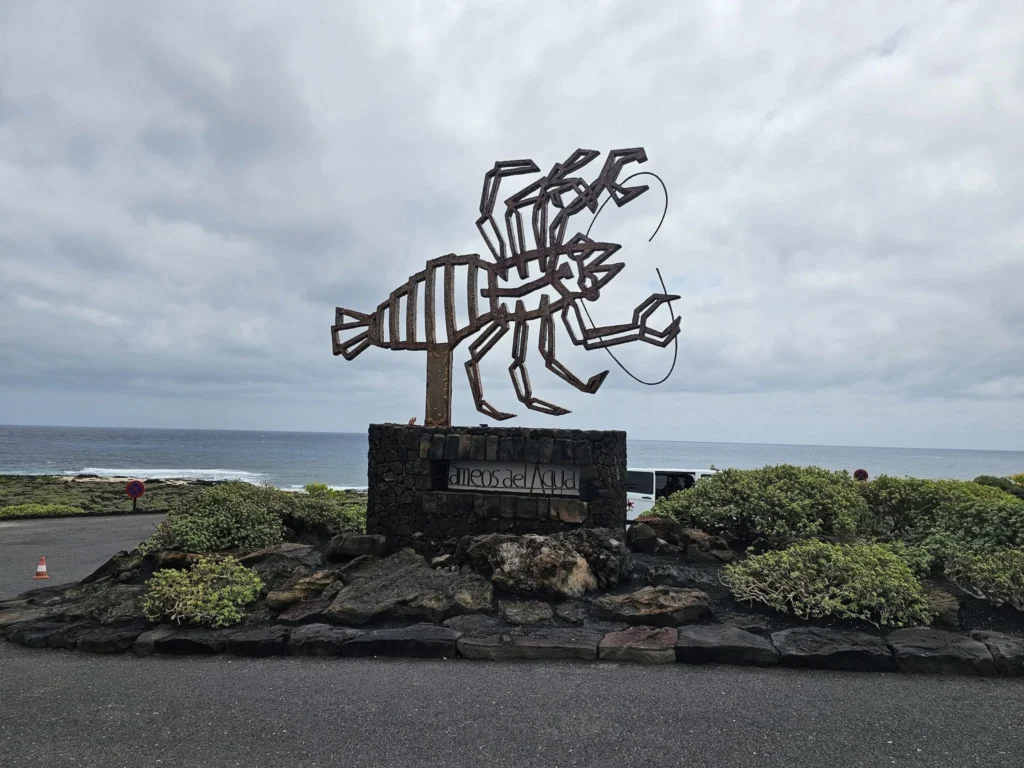 Cruising with Danny and Peter, Holland America Line, Nieuw Statendam, Arrecife, Lanzarote, Canary Islands, Volcanic Adventure | A vibrant collage capturing an adventure in Arrecife, Lanzarote: the dark, winding lava tunnels of Cueva de los Verdes illuminated by soft lights; the serene turquoise pool and lush greenery of Jameos del Agua with its volcanic cave backdrop; the sweeping ocean views from Mirador del Río’s cliffside lookout, framing La Graciosa island; and the surreal, Mars-like red and black lava fields of Timanfaya National Park under a clear sky, showcasing Lanzarote’s volcanic beauty.