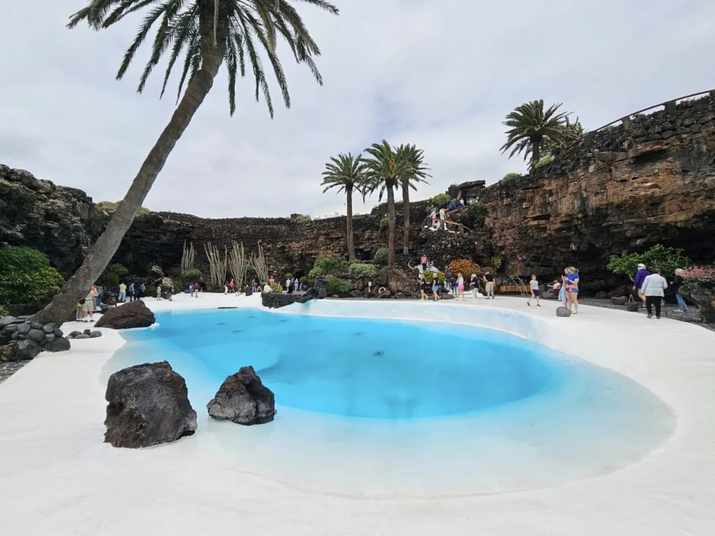 Cruising with Danny and Peter, Holland America Line, Nieuw Statendam, Arrecife, Lanzarote, Canary Islands, Volcanic Adventure | A vibrant collage capturing an adventure in Arrecife, Lanzarote: the dark, winding lava tunnels of Cueva de los Verdes illuminated by soft lights; the serene turquoise pool and lush greenery of Jameos del Agua with its volcanic cave backdrop; the sweeping ocean views from Mirador del Río’s cliffside lookout, framing La Graciosa island; and the surreal, Mars-like red and black lava fields of Timanfaya National Park under a clear sky, showcasing Lanzarote’s volcanic beauty.