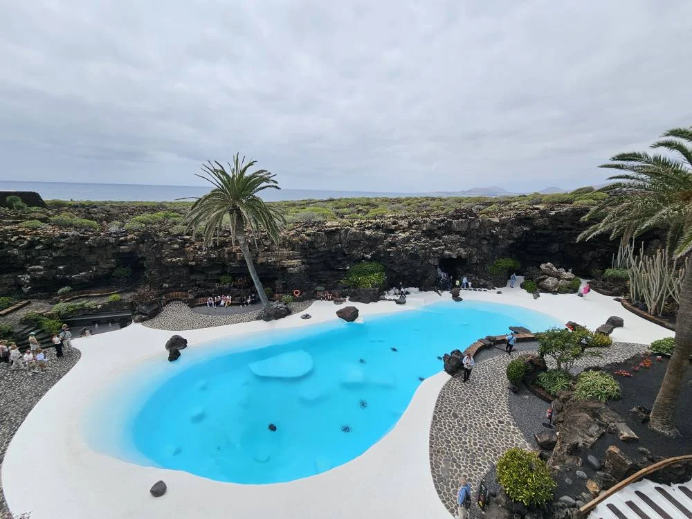 Cruising with Danny and Peter, Holland America Line, Nieuw Statendam, Arrecife, Lanzarote, Canary Islands, Volcanic Adventure | A vibrant collage capturing an adventure in Arrecife, Lanzarote: the dark, winding lava tunnels of Cueva de los Verdes illuminated by soft lights; the serene turquoise pool and lush greenery of Jameos del Agua with its volcanic cave backdrop; the sweeping ocean views from Mirador del Río’s cliffside lookout, framing La Graciosa island; and the surreal, Mars-like red and black lava fields of Timanfaya National Park under a clear sky, showcasing Lanzarote’s volcanic beauty.