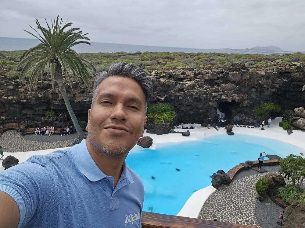 Cruising with Danny and Peter, Holland America Line, Nieuw Statendam, Arrecife, Lanzarote, Canary Islands, Volcanic Adventure | A vibrant collage capturing an adventure in Arrecife, Lanzarote: the dark, winding lava tunnels of Cueva de los Verdes illuminated by soft lights; the serene turquoise pool and lush greenery of Jameos del Agua with its volcanic cave backdrop; the sweeping ocean views from Mirador del Río’s cliffside lookout, framing La Graciosa island; and the surreal, Mars-like red and black lava fields of Timanfaya National Park under a clear sky, showcasing Lanzarote’s volcanic beauty.