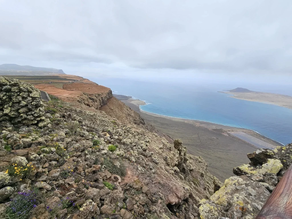 Cruising with Danny and Peter, Holland America Line, Nieuw Statendam, Arrecife, Lanzarote, Canary Islands, Volcanic Adventure | A vibrant collage capturing an adventure in Arrecife, Lanzarote: the dark, winding lava tunnels of Cueva de los Verdes illuminated by soft lights; the serene turquoise pool and lush greenery of Jameos del Agua with its volcanic cave backdrop; the sweeping ocean views from Mirador del Río’s cliffside lookout, framing La Graciosa island; and the surreal, Mars-like red and black lava fields of Timanfaya National Park under a clear sky, showcasing Lanzarote’s volcanic beauty.