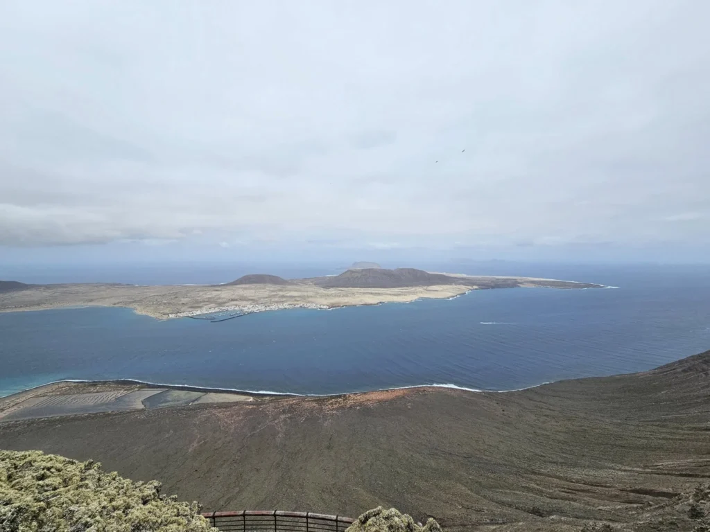 Cruising with Danny and Peter, Holland America Line, Nieuw Statendam, Arrecife, Lanzarote, Canary Islands, Volcanic Adventure | A vibrant collage capturing an adventure in Arrecife, Lanzarote: the dark, winding lava tunnels of Cueva de los Verdes illuminated by soft lights; the serene turquoise pool and lush greenery of Jameos del Agua with its volcanic cave backdrop; the sweeping ocean views from Mirador del Río’s cliffside lookout, framing La Graciosa island; and the surreal, Mars-like red and black lava fields of Timanfaya National Park under a clear sky, showcasing Lanzarote’s volcanic beauty.