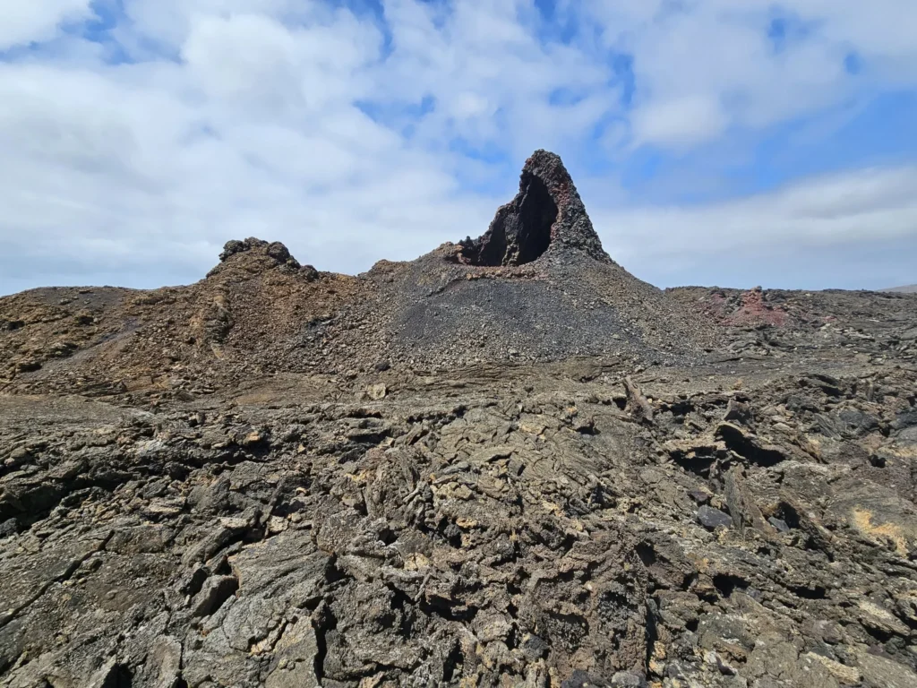 Cruising with Danny and Peter, Holland America Line, Nieuw Statendam, Arrecife, Lanzarote, Canary Islands, Volcanic Adventure | A vibrant collage capturing an adventure in Arrecife, Lanzarote: the dark, winding lava tunnels of Cueva de los Verdes illuminated by soft lights; the serene turquoise pool and lush greenery of Jameos del Agua with its volcanic cave backdrop; the sweeping ocean views from Mirador del Río’s cliffside lookout, framing La Graciosa island; and the surreal, Mars-like red and black lava fields of Timanfaya National Park under a clear sky, showcasing Lanzarote’s volcanic beauty.