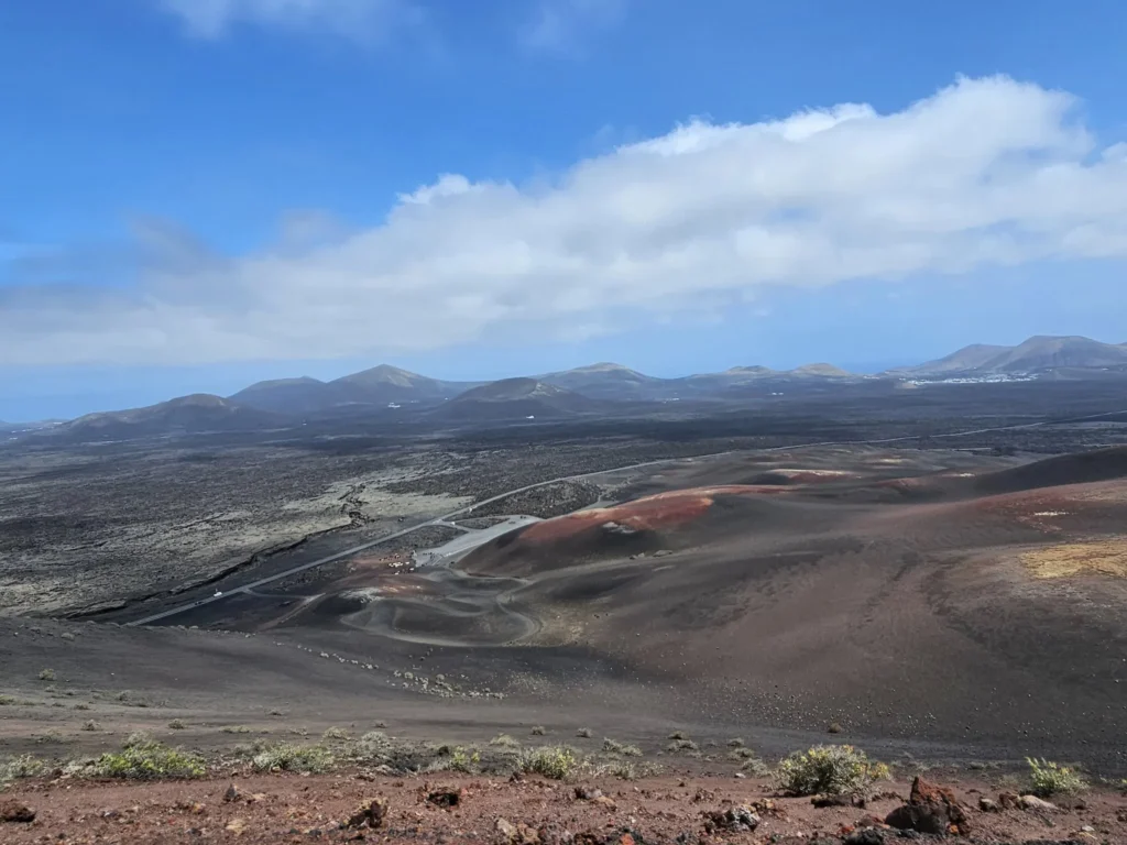 Cruising with Danny and Peter, Holland America Line, Nieuw Statendam, Arrecife, Lanzarote, Canary Islands, Volcanic Adventure | A vibrant collage capturing an adventure in Arrecife, Lanzarote: the dark, winding lava tunnels of Cueva de los Verdes illuminated by soft lights; the serene turquoise pool and lush greenery of Jameos del Agua with its volcanic cave backdrop; the sweeping ocean views from Mirador del Río’s cliffside lookout, framing La Graciosa island; and the surreal, Mars-like red and black lava fields of Timanfaya National Park under a clear sky, showcasing Lanzarote’s volcanic beauty.