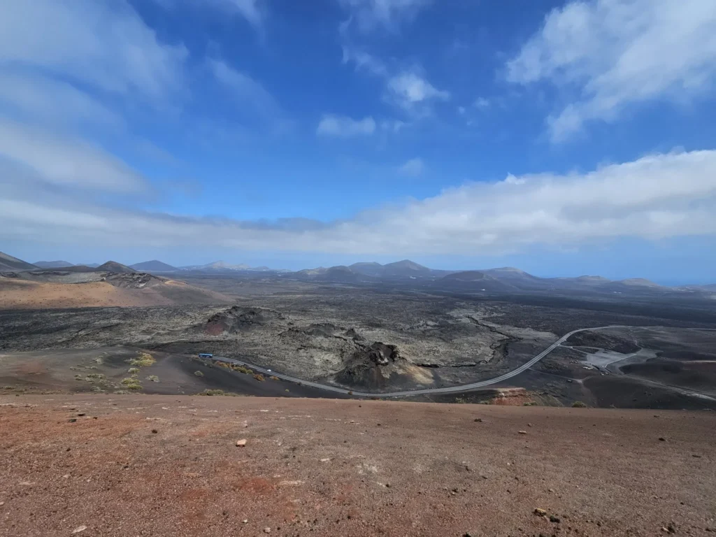 Cruising with Danny and Peter, Holland America Line, Nieuw Statendam, Arrecife, Lanzarote, Canary Islands, Volcanic Adventure | A vibrant collage capturing an adventure in Arrecife, Lanzarote: the dark, winding lava tunnels of Cueva de los Verdes illuminated by soft lights; the serene turquoise pool and lush greenery of Jameos del Agua with its volcanic cave backdrop; the sweeping ocean views from Mirador del Río’s cliffside lookout, framing La Graciosa island; and the surreal, Mars-like red and black lava fields of Timanfaya National Park under a clear sky, showcasing Lanzarote’s volcanic beauty.