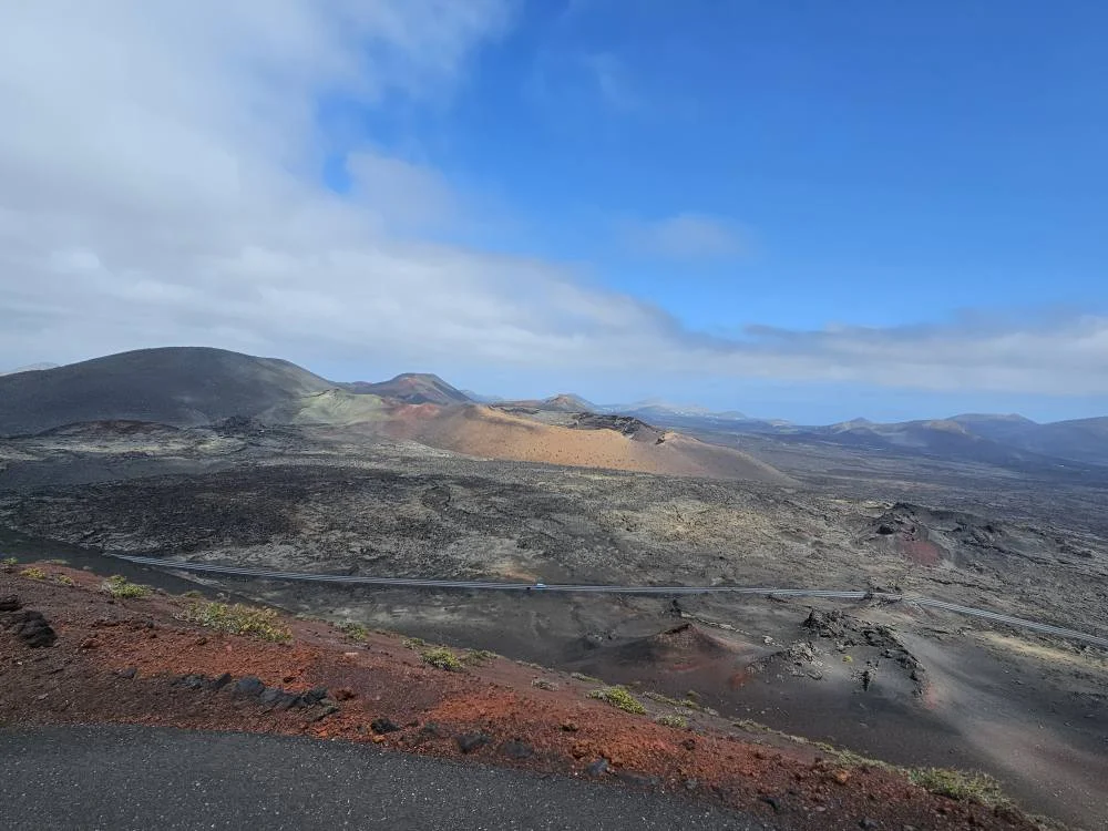 Cruising with Danny and Peter, Holland America Line, Nieuw Statendam, Arrecife, Lanzarote, Canary Islands, Volcanic Adventure | A vibrant collage capturing an adventure in Arrecife, Lanzarote: the dark, winding lava tunnels of Cueva de los Verdes illuminated by soft lights; the serene turquoise pool and lush greenery of Jameos del Agua with its volcanic cave backdrop; the sweeping ocean views from Mirador del Río’s cliffside lookout, framing La Graciosa island; and the surreal, Mars-like red and black lava fields of Timanfaya National Park under a clear sky, showcasing Lanzarote’s volcanic beauty.