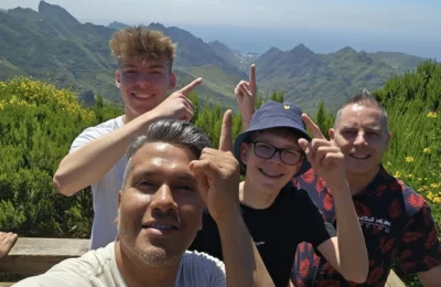 Cruising with Danny and Peter, Holland America Line, Nieuw Statendam, Santa Cruz, Tenerife, Canary Islands, History Adventure | A vibrant collage capturing Santa Cruz, Tenerife’s diverse beauty: the misty, lush laurel forests of Anaga Rural Park with sunlight filtering through dense green foliage at Mirador Cruz del Carmen; a panoramic view from Mirador Pico del Inglés showcasing rugged Anaga Mountains and the distant Atlantic Ocean under a partly cloudy sky; the golden sands of Playa de las Teresitas lined with palm trees and calm turquoise waters; a colorful seafood platter with grilled prawns and papas arrugadas served at a beachfront restaurant; and the elegant Nieuw Statendam cruise ship docked at Santa Cruz port with the city’s skyline and Anaga Mountains in the background.