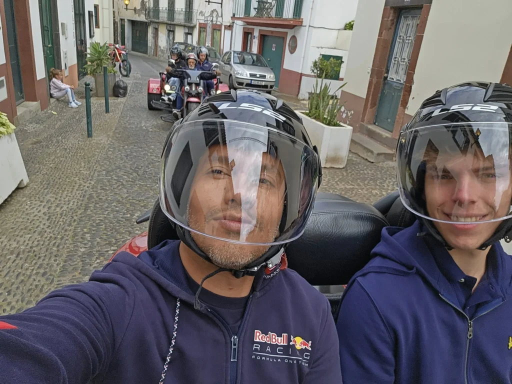 Cruising with Danny and Peter, Holland America Line, Nieuw Statendam, Funchal, Madeira. Portugal, History Adventure | A vibrant collage capturing a day in Funchal, Madeira: a sleek trike navigates winding roads with lush green hills in the background; the panoramic view from Pico dos Barcelos showcases Funchal Bay and the Desertas Islands under a clear sky; Cascata dos Anjos waterfall cascades from cliffs onto a road, surrounded by verdant greenery; Praia da Madalena do Mar’s pebbled beach and black volcanic sand meet gentle waves with towering cliffs above; the misty Valley of the Nuns nestles between rugged mountains, dotted with stone houses and chestnut groves; Cabo Girão’s glass-bottomed skywalk reveals a dizzying drop to the Atlantic and terraced fields below; a plate of warm bolo do caco flatbread filled with steak sits on a café table in Funchal’s colorful old town; the CR7 Museum displays Cristiano Ronaldo’s trophies and jerseys with a waterfront view of the Nieuw Statendam; and Nami Sushi Bar’s elegant sushi platter gleams under soft lighting aboard the ship.