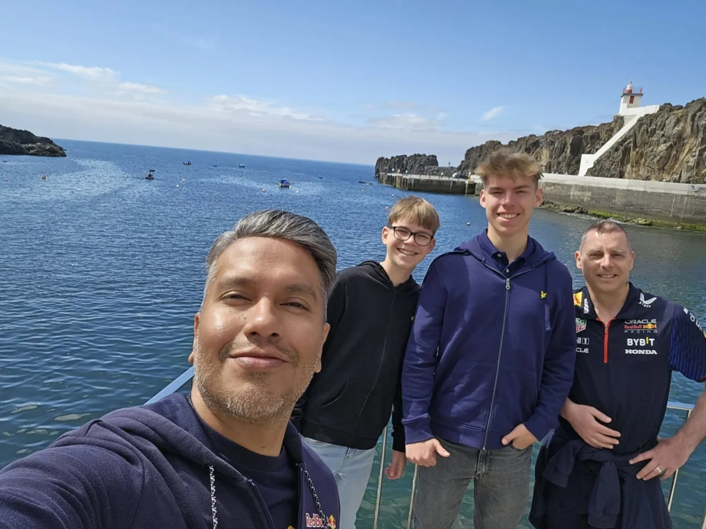 Cruising with Danny and Peter, Holland America Line, Nieuw Statendam, Funchal, Madeira. Portugal, History Adventure | A vibrant collage capturing a day in Funchal, Madeira: a sleek trike navigates winding roads with lush green hills in the background; the panoramic view from Pico dos Barcelos showcases Funchal Bay and the Desertas Islands under a clear sky; Cascata dos Anjos waterfall cascades from cliffs onto a road, surrounded by verdant greenery; Praia da Madalena do Mar’s pebbled beach and black volcanic sand meet gentle waves with towering cliffs above; the misty Valley of the Nuns nestles between rugged mountains, dotted with stone houses and chestnut groves; Cabo Girão’s glass-bottomed skywalk reveals a dizzying drop to the Atlantic and terraced fields below; a plate of warm bolo do caco flatbread filled with steak sits on a café table in Funchal’s colorful old town; the CR7 Museum displays Cristiano Ronaldo’s trophies and jerseys with a waterfront view of the Nieuw Statendam; and Nami Sushi Bar’s elegant sushi platter gleams under soft lighting aboard the ship.