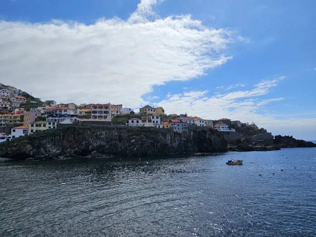 Cruising with Danny and Peter, Holland America Line, Nieuw Statendam, Funchal, Madeira. Portugal, History Adventure | A vibrant collage capturing a day in Funchal, Madeira: a sleek trike navigates winding roads with lush green hills in the background; the panoramic view from Pico dos Barcelos showcases Funchal Bay and the Desertas Islands under a clear sky; Cascata dos Anjos waterfall cascades from cliffs onto a road, surrounded by verdant greenery; Praia da Madalena do Mar’s pebbled beach and black volcanic sand meet gentle waves with towering cliffs above; the misty Valley of the Nuns nestles between rugged mountains, dotted with stone houses and chestnut groves; Cabo Girão’s glass-bottomed skywalk reveals a dizzying drop to the Atlantic and terraced fields below; a plate of warm bolo do caco flatbread filled with steak sits on a café table in Funchal’s colorful old town; the CR7 Museum displays Cristiano Ronaldo’s trophies and jerseys with a waterfront view of the Nieuw Statendam; and Nami Sushi Bar’s elegant sushi platter gleams under soft lighting aboard the ship.