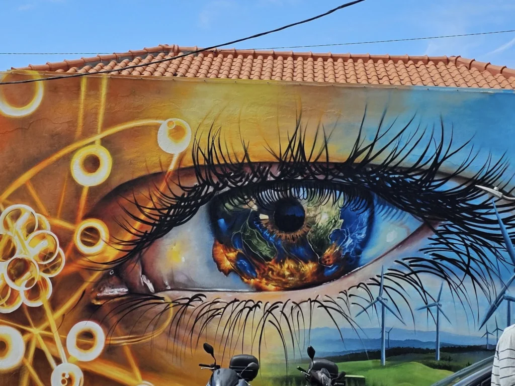 Cruising with Danny and Peter, Holland America Line, Nieuw Statendam, Funchal, Madeira. Portugal, History Adventure | A vibrant collage capturing a day in Funchal, Madeira: a sleek trike navigates winding roads with lush green hills in the background; the panoramic view from Pico dos Barcelos showcases Funchal Bay and the Desertas Islands under a clear sky; Cascata dos Anjos waterfall cascades from cliffs onto a road, surrounded by verdant greenery; Praia da Madalena do Mar’s pebbled beach and black volcanic sand meet gentle waves with towering cliffs above; the misty Valley of the Nuns nestles between rugged mountains, dotted with stone houses and chestnut groves; Cabo Girão’s glass-bottomed skywalk reveals a dizzying drop to the Atlantic and terraced fields below; a plate of warm bolo do caco flatbread filled with steak sits on a café table in Funchal’s colorful old town; the CR7 Museum displays Cristiano Ronaldo’s trophies and jerseys with a waterfront view of the Nieuw Statendam; and Nami Sushi Bar’s elegant sushi platter gleams under soft lighting aboard the ship.