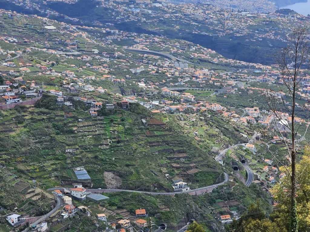 Cruising with Danny and Peter, Holland America Line, Nieuw Statendam, Funchal, Madeira. Portugal, History Adventure | A vibrant collage capturing a day in Funchal, Madeira: a sleek trike navigates winding roads with lush green hills in the background; the panoramic view from Pico dos Barcelos showcases Funchal Bay and the Desertas Islands under a clear sky; Cascata dos Anjos waterfall cascades from cliffs onto a road, surrounded by verdant greenery; Praia da Madalena do Mar’s pebbled beach and black volcanic sand meet gentle waves with towering cliffs above; the misty Valley of the Nuns nestles between rugged mountains, dotted with stone houses and chestnut groves; Cabo Girão’s glass-bottomed skywalk reveals a dizzying drop to the Atlantic and terraced fields below; a plate of warm bolo do caco flatbread filled with steak sits on a café table in Funchal’s colorful old town; the CR7 Museum displays Cristiano Ronaldo’s trophies and jerseys with a waterfront view of the Nieuw Statendam; and Nami Sushi Bar’s elegant sushi platter gleams under soft lighting aboard the ship.