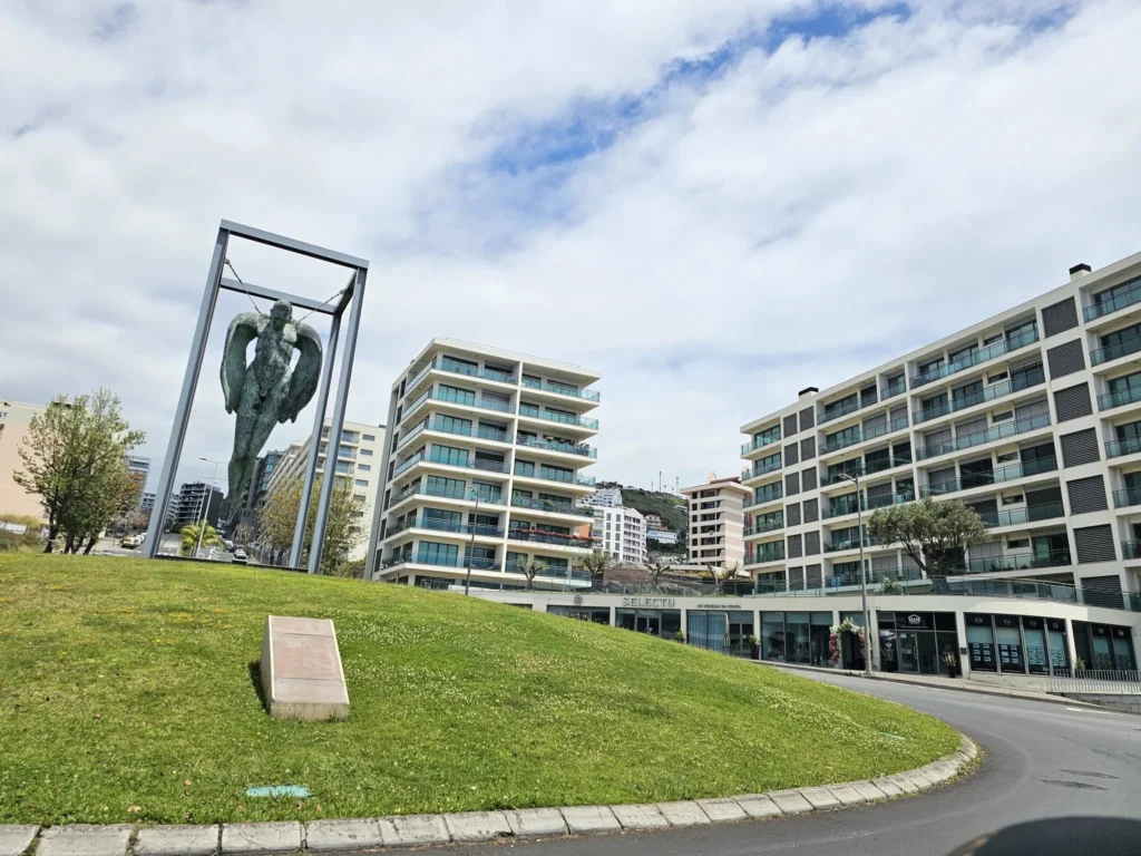 Cruising with Danny and Peter, Holland America Line, Nieuw Statendam, Funchal, Madeira. Portugal, History Adventure | A vibrant collage capturing a day in Funchal, Madeira: a sleek trike navigates winding roads with lush green hills in the background; the panoramic view from Pico dos Barcelos showcases Funchal Bay and the Desertas Islands under a clear sky; Cascata dos Anjos waterfall cascades from cliffs onto a road, surrounded by verdant greenery; Praia da Madalena do Mar’s pebbled beach and black volcanic sand meet gentle waves with towering cliffs above; the misty Valley of the Nuns nestles between rugged mountains, dotted with stone houses and chestnut groves; Cabo Girão’s glass-bottomed skywalk reveals a dizzying drop to the Atlantic and terraced fields below; a plate of warm bolo do caco flatbread filled with steak sits on a café table in Funchal’s colorful old town; the CR7 Museum displays Cristiano Ronaldo’s trophies and jerseys with a waterfront view of the Nieuw Statendam; and Nami Sushi Bar’s elegant sushi platter gleams under soft lighting aboard the ship.