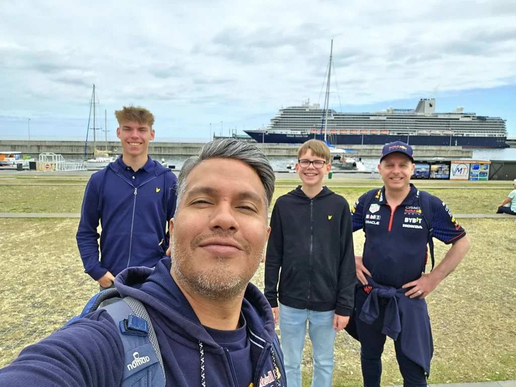 Cruising with Danny and Peter, Holland America Line, Nieuw Statendam, Funchal, Madeira. Portugal, History Adventure | A vibrant collage capturing a day in Funchal, Madeira: a sleek trike navigates winding roads with lush green hills in the background; the panoramic view from Pico dos Barcelos showcases Funchal Bay and the Desertas Islands under a clear sky; Cascata dos Anjos waterfall cascades from cliffs onto a road, surrounded by verdant greenery; Praia da Madalena do Mar’s pebbled beach and black volcanic sand meet gentle waves with towering cliffs above; the misty Valley of the Nuns nestles between rugged mountains, dotted with stone houses and chestnut groves; Cabo Girão’s glass-bottomed skywalk reveals a dizzying drop to the Atlantic and terraced fields below; a plate of warm bolo do caco flatbread filled with steak sits on a café table in Funchal’s colorful old town; the CR7 Museum displays Cristiano Ronaldo’s trophies and jerseys with a waterfront view of the Nieuw Statendam; and Nami Sushi Bar’s elegant sushi platter gleams under soft lighting aboard the ship.