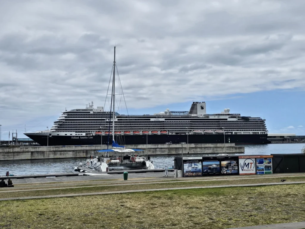 Cruising with Danny and Peter, Holland America Line, Nieuw Statendam, Funchal, Madeira. Portugal, History Adventure | A vibrant collage capturing a day in Funchal, Madeira: a sleek trike navigates winding roads with lush green hills in the background; the panoramic view from Pico dos Barcelos showcases Funchal Bay and the Desertas Islands under a clear sky; Cascata dos Anjos waterfall cascades from cliffs onto a road, surrounded by verdant greenery; Praia da Madalena do Mar’s pebbled beach and black volcanic sand meet gentle waves with towering cliffs above; the misty Valley of the Nuns nestles between rugged mountains, dotted with stone houses and chestnut groves; Cabo Girão’s glass-bottomed skywalk reveals a dizzying drop to the Atlantic and terraced fields below; a plate of warm bolo do caco flatbread filled with steak sits on a café table in Funchal’s colorful old town; the CR7 Museum displays Cristiano Ronaldo’s trophies and jerseys with a waterfront view of the Nieuw Statendam; and Nami Sushi Bar’s elegant sushi platter gleams under soft lighting aboard the ship.
