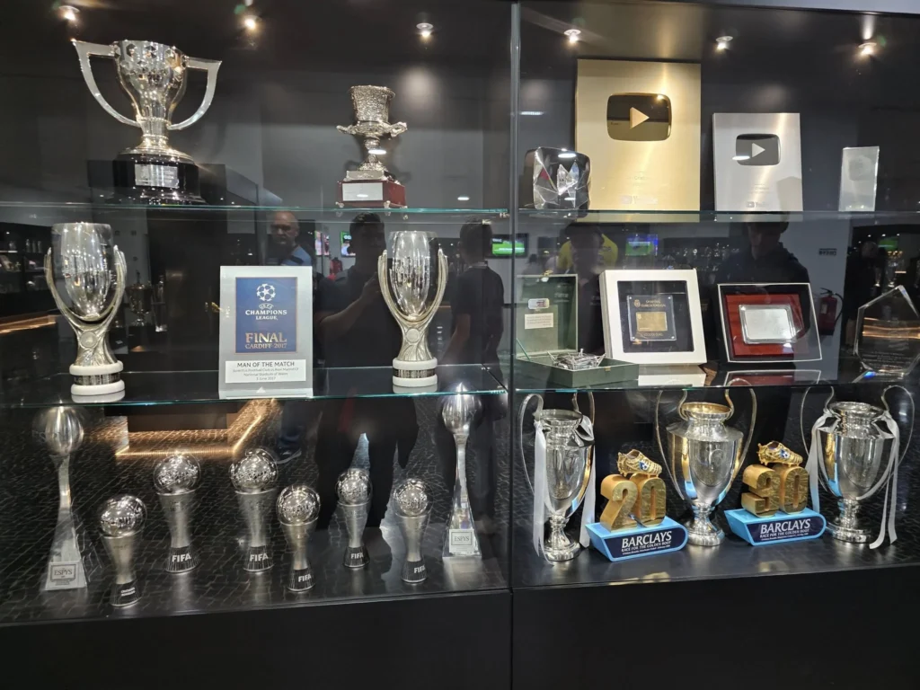 Cruising with Danny and Peter, Holland America Line, Nieuw Statendam, Funchal, Madeira. Portugal, History Adventure | A vibrant collage capturing a day in Funchal, Madeira: a sleek trike navigates winding roads with lush green hills in the background; the panoramic view from Pico dos Barcelos showcases Funchal Bay and the Desertas Islands under a clear sky; Cascata dos Anjos waterfall cascades from cliffs onto a road, surrounded by verdant greenery; Praia da Madalena do Mar’s pebbled beach and black volcanic sand meet gentle waves with towering cliffs above; the misty Valley of the Nuns nestles between rugged mountains, dotted with stone houses and chestnut groves; Cabo Girão’s glass-bottomed skywalk reveals a dizzying drop to the Atlantic and terraced fields below; a plate of warm bolo do caco flatbread filled with steak sits on a café table in Funchal’s colorful old town; the CR7 Museum displays Cristiano Ronaldo’s trophies and jerseys with a waterfront view of the Nieuw Statendam; and Nami Sushi Bar’s elegant sushi platter gleams under soft lighting aboard the ship.