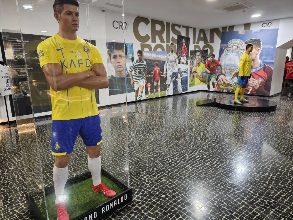 Cruising with Danny and Peter, Holland America Line, Nieuw Statendam, Funchal, Madeira. Portugal, History Adventure | A vibrant collage capturing a day in Funchal, Madeira: a sleek trike navigates winding roads with lush green hills in the background; the panoramic view from Pico dos Barcelos showcases Funchal Bay and the Desertas Islands under a clear sky; Cascata dos Anjos waterfall cascades from cliffs onto a road, surrounded by verdant greenery; Praia da Madalena do Mar’s pebbled beach and black volcanic sand meet gentle waves with towering cliffs above; the misty Valley of the Nuns nestles between rugged mountains, dotted with stone houses and chestnut groves; Cabo Girão’s glass-bottomed skywalk reveals a dizzying drop to the Atlantic and terraced fields below; a plate of warm bolo do caco flatbread filled with steak sits on a café table in Funchal’s colorful old town; the CR7 Museum displays Cristiano Ronaldo’s trophies and jerseys with a waterfront view of the Nieuw Statendam; and Nami Sushi Bar’s elegant sushi platter gleams under soft lighting aboard the ship.