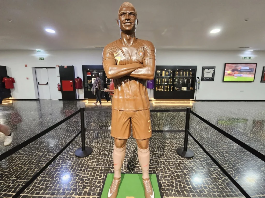 Cruising with Danny and Peter, Holland America Line, Nieuw Statendam, Funchal, Madeira. Portugal, History Adventure | A vibrant collage capturing a day in Funchal, Madeira: a sleek trike navigates winding roads with lush green hills in the background; the panoramic view from Pico dos Barcelos showcases Funchal Bay and the Desertas Islands under a clear sky; Cascata dos Anjos waterfall cascades from cliffs onto a road, surrounded by verdant greenery; Praia da Madalena do Mar’s pebbled beach and black volcanic sand meet gentle waves with towering cliffs above; the misty Valley of the Nuns nestles between rugged mountains, dotted with stone houses and chestnut groves; Cabo Girão’s glass-bottomed skywalk reveals a dizzying drop to the Atlantic and terraced fields below; a plate of warm bolo do caco flatbread filled with steak sits on a café table in Funchal’s colorful old town; the CR7 Museum displays Cristiano Ronaldo’s trophies and jerseys with a waterfront view of the Nieuw Statendam; and Nami Sushi Bar’s elegant sushi platter gleams under soft lighting aboard the ship.