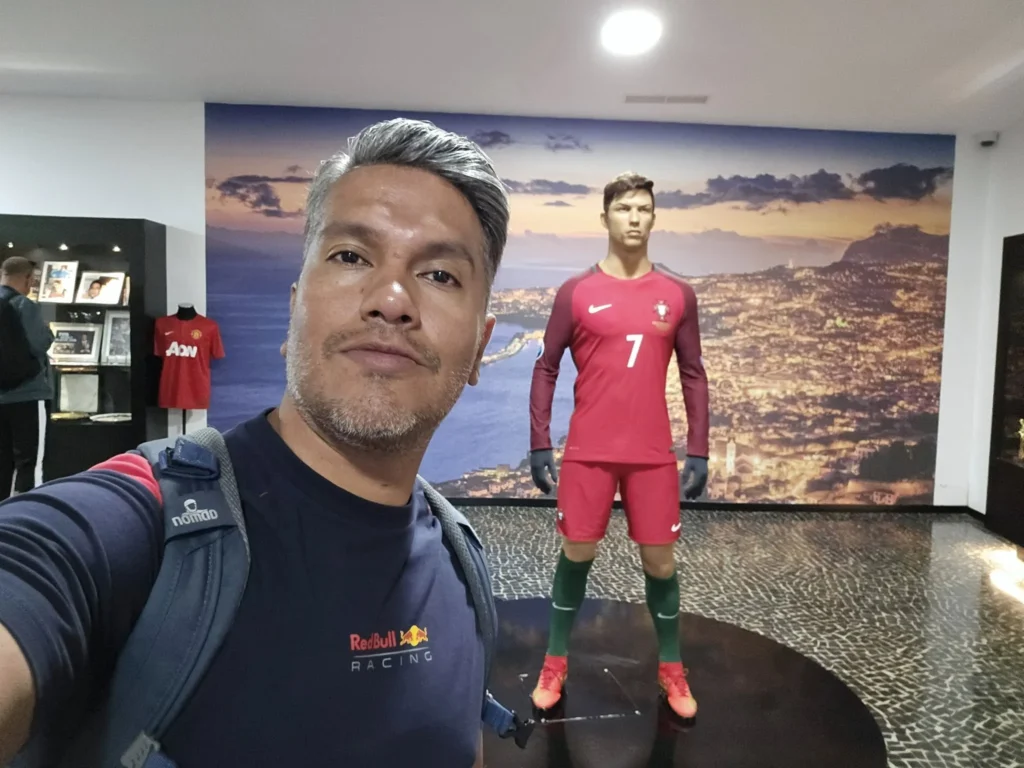 Cruising with Danny and Peter, Holland America Line, Nieuw Statendam, Funchal, Madeira. Portugal, History Adventure | A vibrant collage capturing a day in Funchal, Madeira: a sleek trike navigates winding roads with lush green hills in the background; the panoramic view from Pico dos Barcelos showcases Funchal Bay and the Desertas Islands under a clear sky; Cascata dos Anjos waterfall cascades from cliffs onto a road, surrounded by verdant greenery; Praia da Madalena do Mar’s pebbled beach and black volcanic sand meet gentle waves with towering cliffs above; the misty Valley of the Nuns nestles between rugged mountains, dotted with stone houses and chestnut groves; Cabo Girão’s glass-bottomed skywalk reveals a dizzying drop to the Atlantic and terraced fields below; a plate of warm bolo do caco flatbread filled with steak sits on a café table in Funchal’s colorful old town; the CR7 Museum displays Cristiano Ronaldo’s trophies and jerseys with a waterfront view of the Nieuw Statendam; and Nami Sushi Bar’s elegant sushi platter gleams under soft lighting aboard the ship.